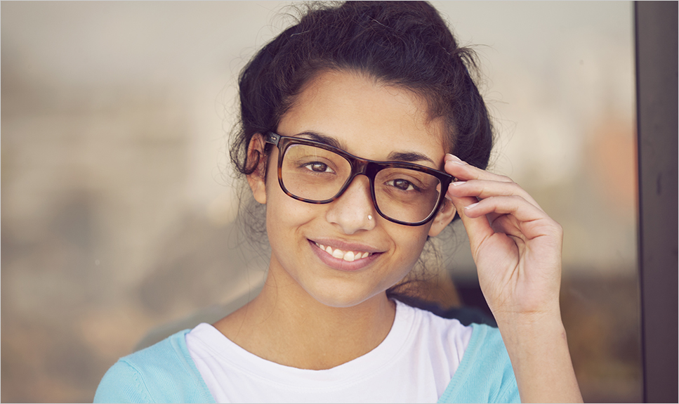 Niña sonriendo mirando con lentes.