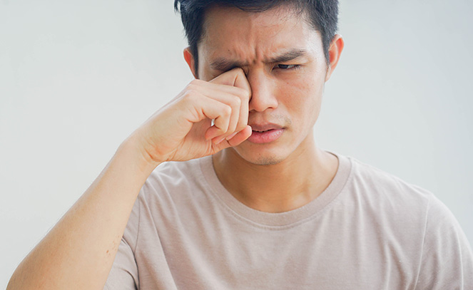 Joven frotándose los ojos por ojo seco
