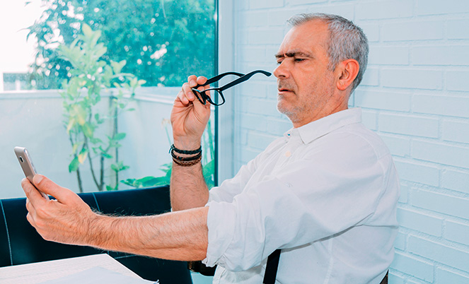 Adulto mayor que no puede leer en su celular sin usar lentes