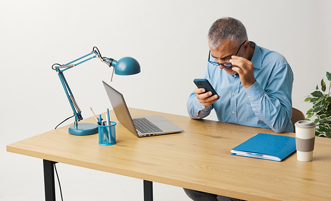 Persona de la tercera edad frente a la computadora y con malestar en los ojos