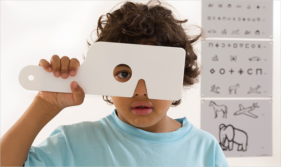 Niño tapándose un ojo para hacer una prueba oftalmológica.