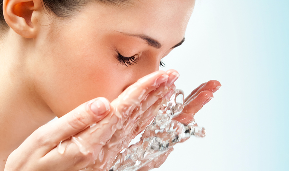 Mujer enjuagándose los ojos con agua.